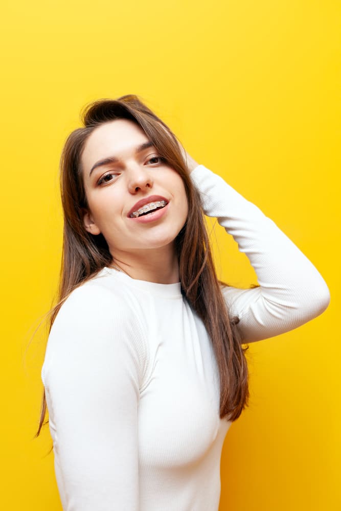 Smiling confidently with clear braces by Carpinello Orthodontics in Drexel Hill, PA, a young woman poses.