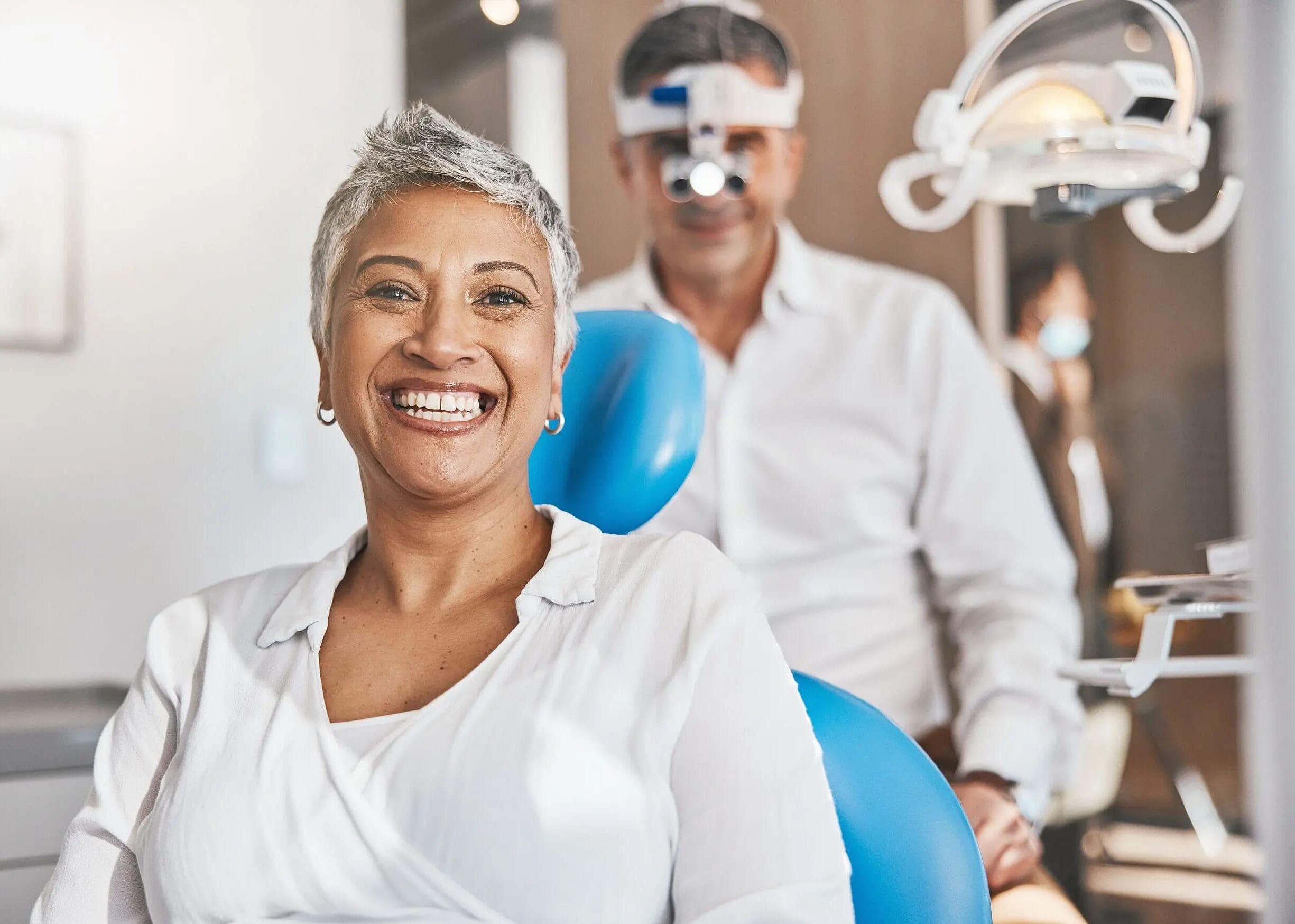 At Carpinello Orthodontics in Drexel Hill, Newtown Square, or Edgmont, PA, a smiling woman sits in a dental exam chair, highlighting specific dental issues in adult orthodontics.