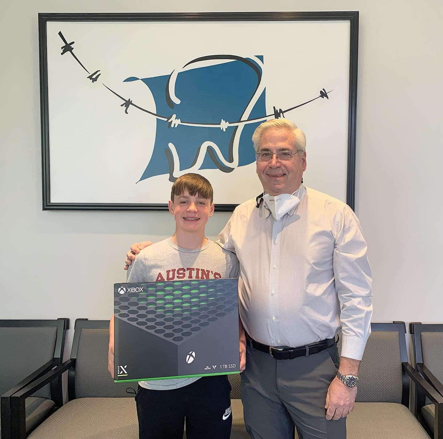At Carpinello Orthodontics in Drexel Hill, Newtown Square or Edgmont, PA, a smiling boy with an Xbox stands by Dr. Paul Carpinello.