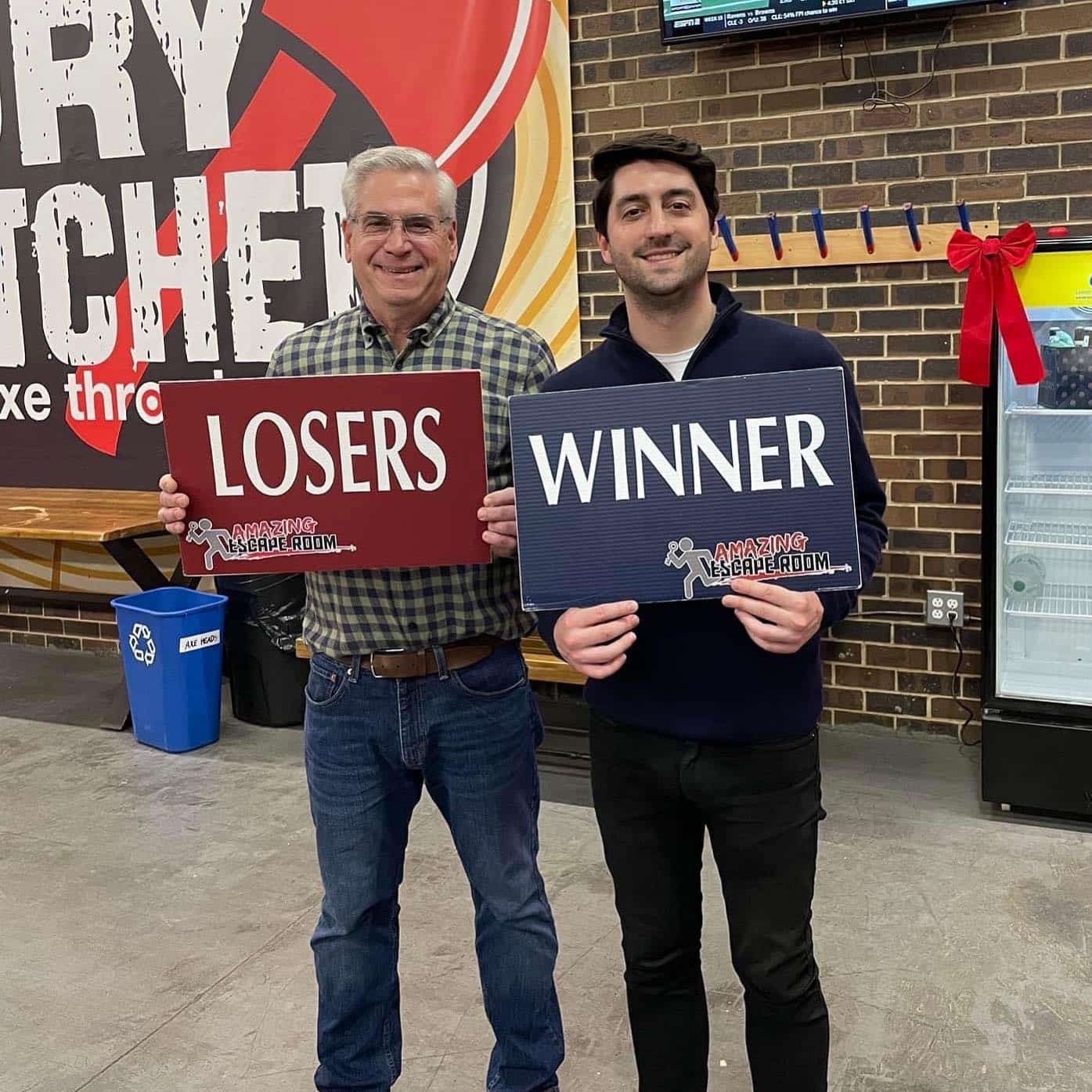 At Carpinello Orthodontics in Drexel Hill, Newtown Square or Edgmont, PA, two smiling men hold "LOSERS" and "WINNER" signs.