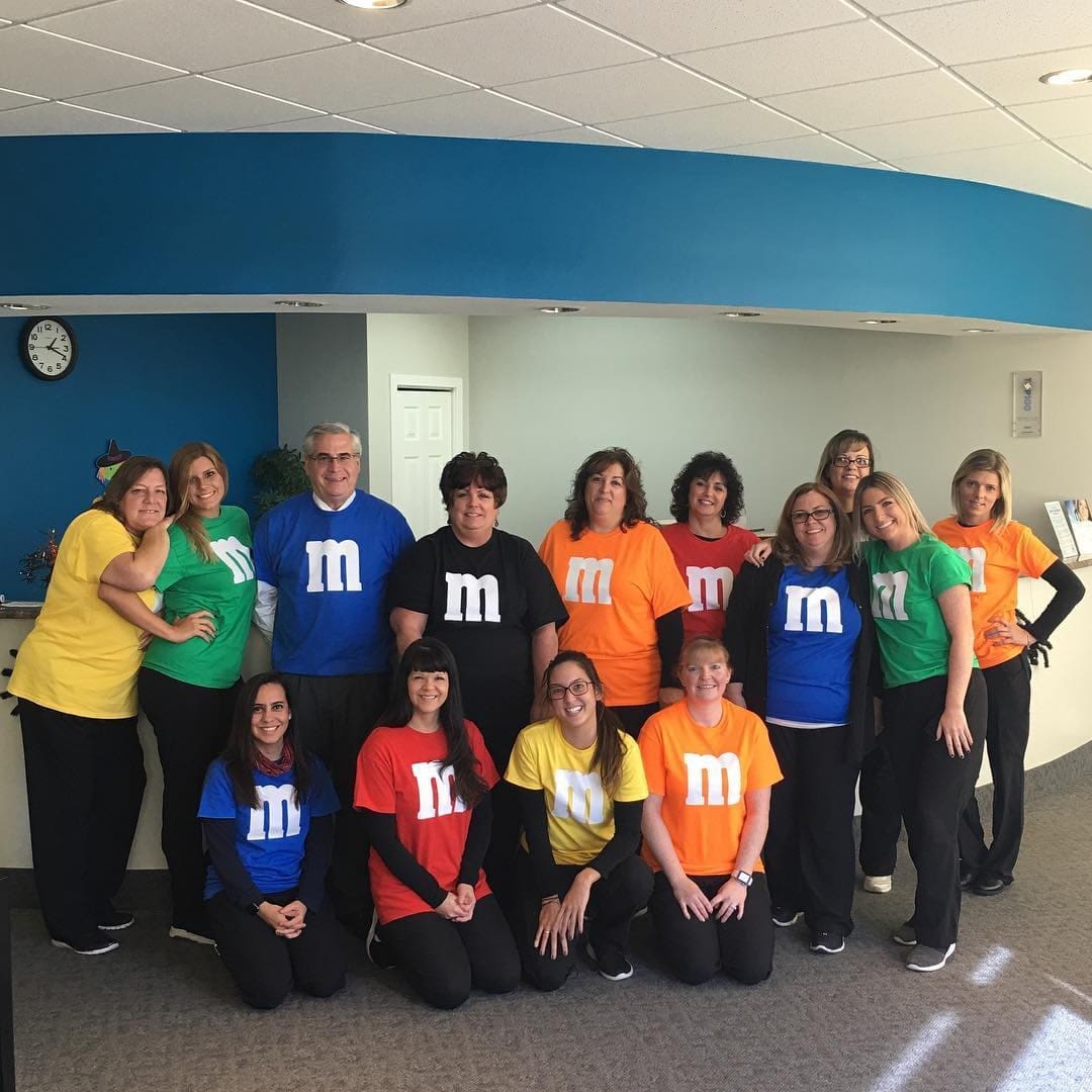 All PPO Insurance Plans Accepted: Orthodontist with Payment Plans Near You A group at Carpinello Orthodontics in Drexel Hill, Newtown Square or Edgmont, PA pose indoors wearing colorful M&M shirts.